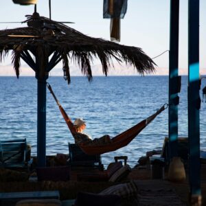 Woman enjoying leisure time in a hammock by the ocean during twilight. Perfect vacation scene.